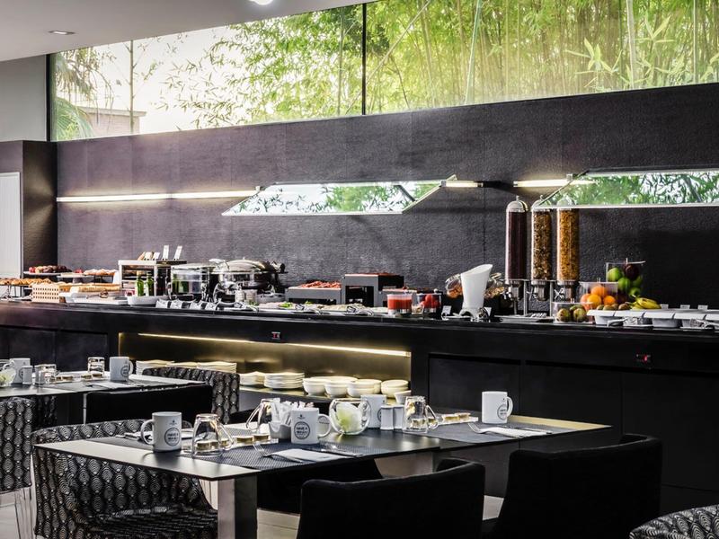 Modern restaurant with set tables and long buffet counter in the background.