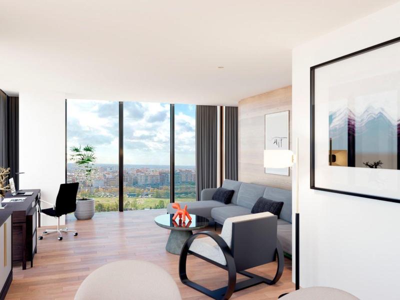 Bright living room with large windows, sofa, desk, and city view.