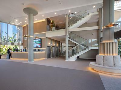Helles, modernes Hotel-Foyer mit Treppe, Sitzbereich und großen Fenstern