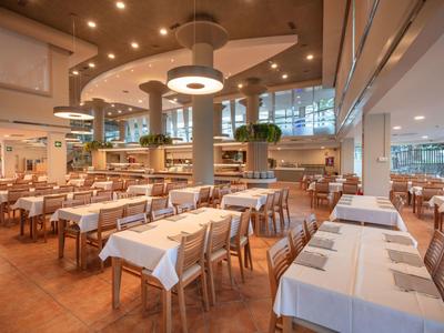 Großer heller Speisesaal mit vielen Tischen und weißen Tischdecken