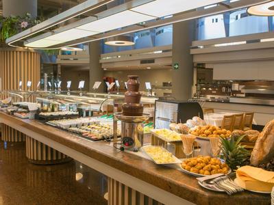 Buffetbereich mit vielfältigen Speisen und Schokoladenbrunnen in einem modernen Hotel.