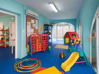 Barevná dětská herna s klouzačkou, domečkem a hračkami v světlé místnosti.