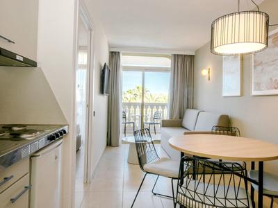 Světý obývací pokoj s jídelním stolem, židlemi, pohovkou a balkonem s výhledem na hory.