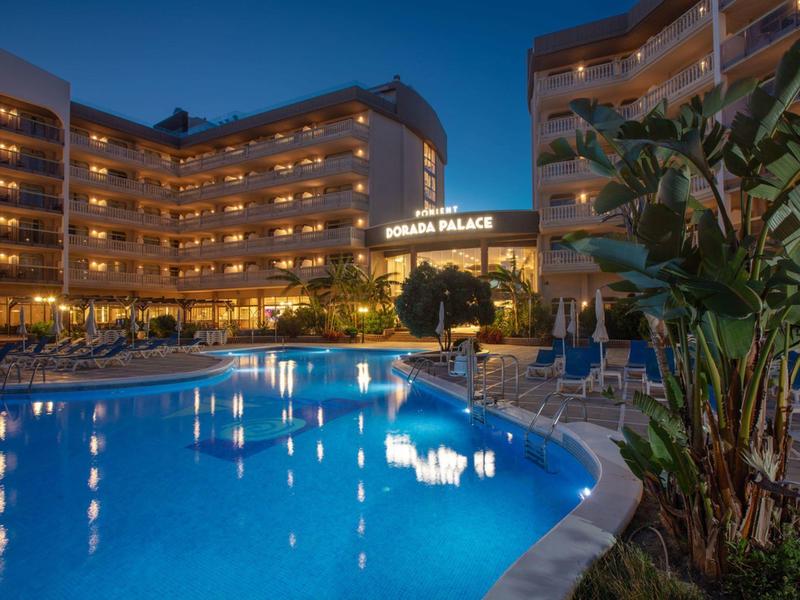 Hotel s osvětleným bazénem a několika patry za soumraku