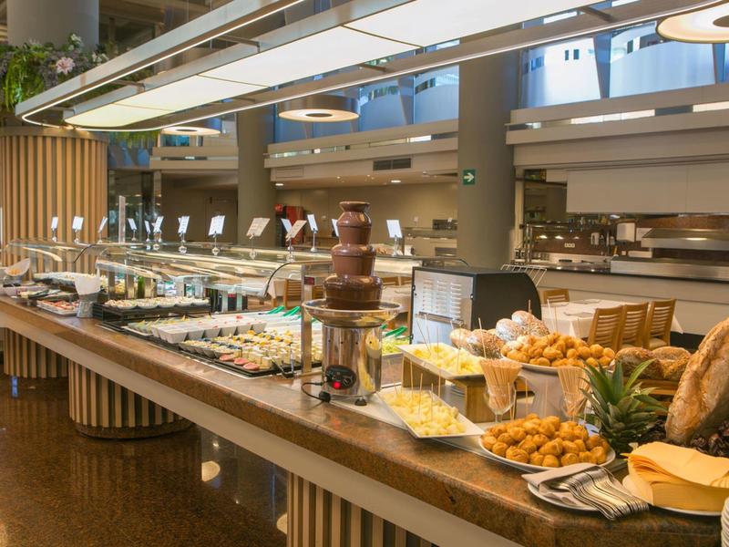 Bufet s různými jídly a čokoládovou fontánou v moderním hotelovém salonku.