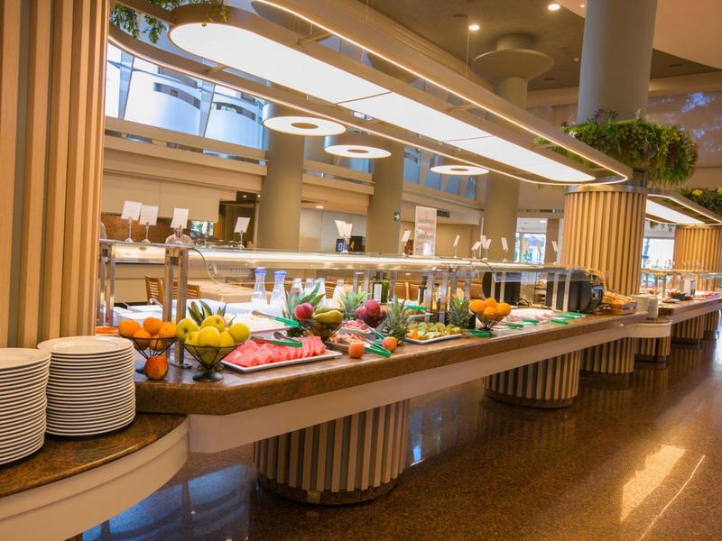 Moderní bufet s čerstvým ovocem a nádobím ve stylové hotelové restauraci.