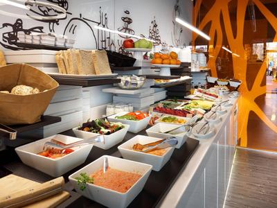 Buffet mit verschiedenen Salaten und Brotauswahl in einem modernen Speiseraum.