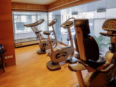 Moderner Fitnessraum mit mehreren Heimtrainern und großen Fenstern mit Stadtblick.