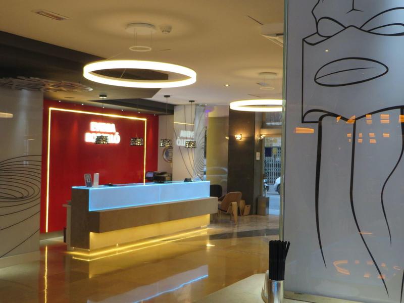 Modern hotel lobby with illuminated reception desk and artistic wall design.
