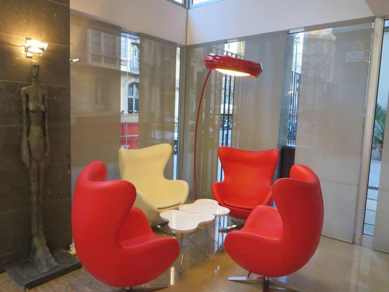Modern seating area with three red and one white designer armchairs in a bright room.
