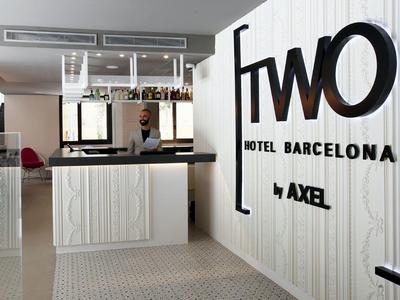 Moderne Hotelrezeption mit weißem Holz, großer Schrift ?fwo? an der Wand und Barkeeper hinter Tresen.