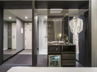 Modern hotel room area with minibar, bathrobe, and lighting.