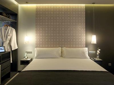 Modern hotel room with large bed, bedside lamps, and open wardrobe.