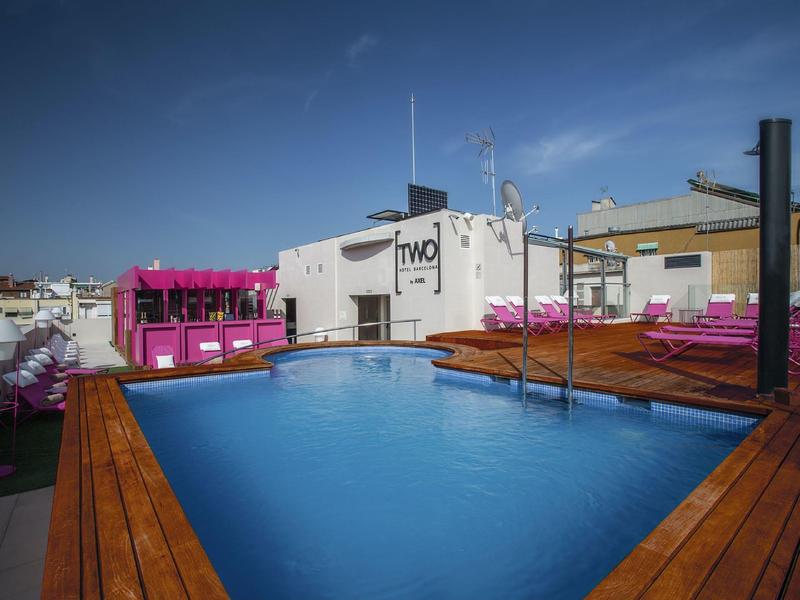 Rooftop pool with blue lounge chairs and wooden deck under clear sky
