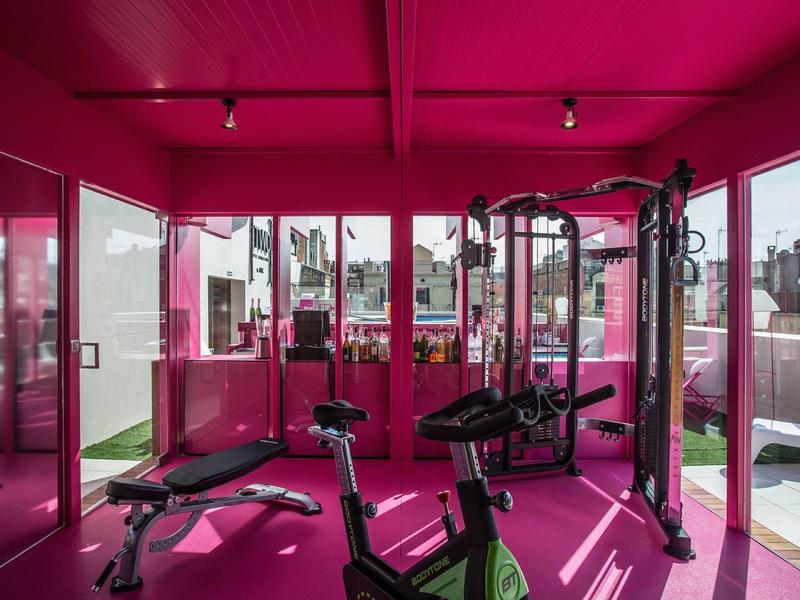Modern gym with pink accents and large windows overlooking the city