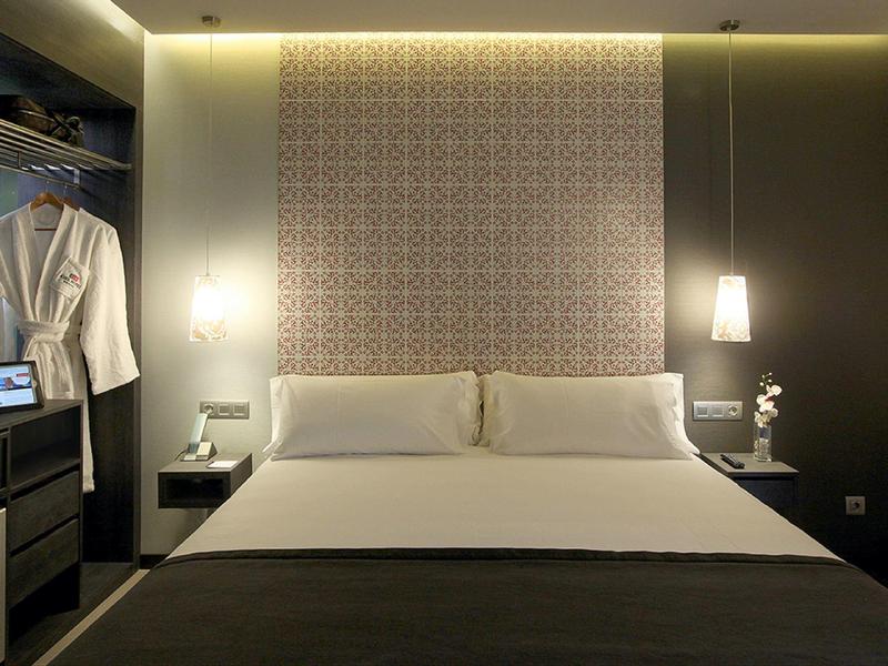 Modern hotel room with large bed, bedside lamps, and open wardrobe.