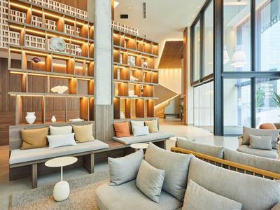 Modern ingerichte hotellobby met comfortabele banken en decoratieve planken.