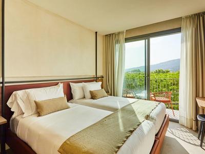 Camera d'hotel moderna con due letti, vista sulle montagne e luce naturale.