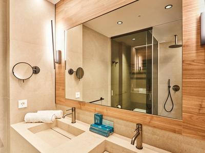 Bagno elegante con doppi lavandini, grande specchio e doccia moderna in vetro.