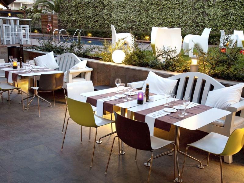 Verlichte buitentafels van een restaurant met stoelen en kussens in een gezellige avondsetting