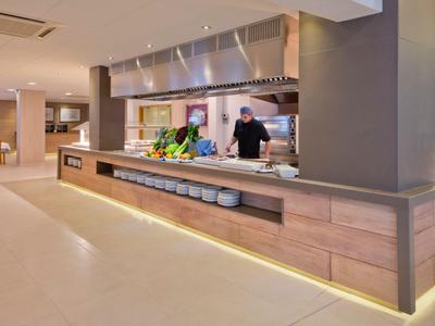 Moderne hotel eetruimte met een lange counter en open keuken op de achtergrond.