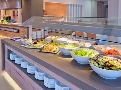 Buffet con varie insalate e piatti caldi in un ambiente di ristorante moderno.