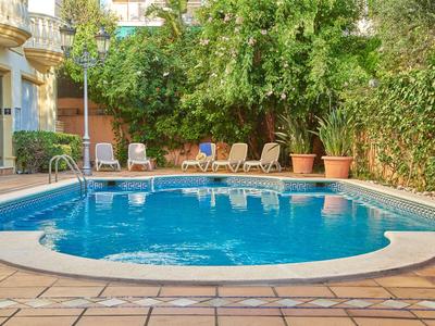 Vue d'une petite piscine d'hôtel avec chaises longues et plantes vertes en arrière-plan.