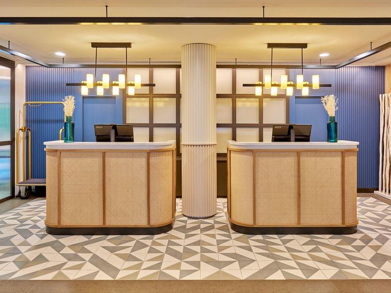 Moderne hotelreceptie met twee balies en decoratieve verlichting.