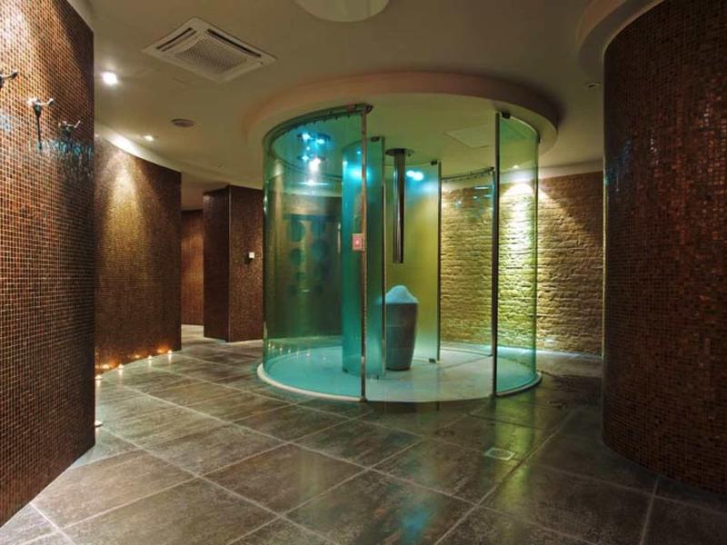 Moderner Wellnessbereich mit großem, rundem Dampfbad aus Glas und warmem, indirektem Licht.