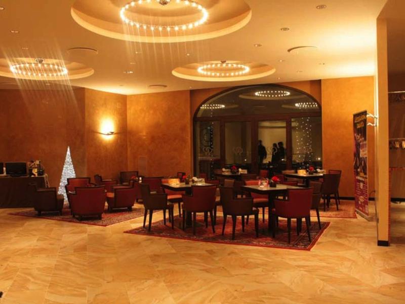 Eleganter Raum mit runden Tischen, Sesseln, warmem Holzfußboden und stilvollen Deckenlampen.