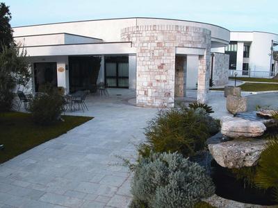 Modernes Haus mit runden und rechteckigen Formen, Steinplattenweg und gepflegtem Garten.