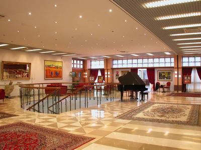 Großer heller Raum mit Marmorfußboden, Flügel, roten Sesseln und großen Fenstern.