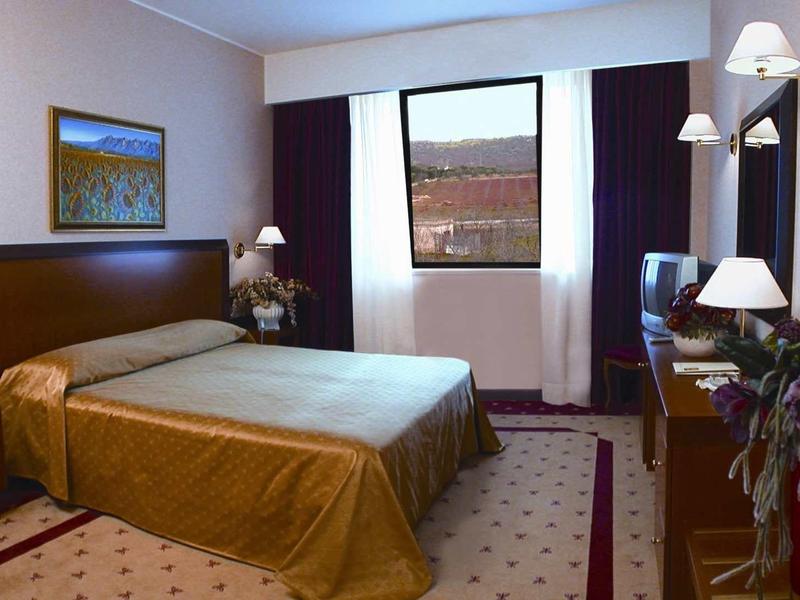Gemütliches Hotelzimmer mit Doppelbett, Teppichboden, Fernseher und Fenster mit Vorhängen.