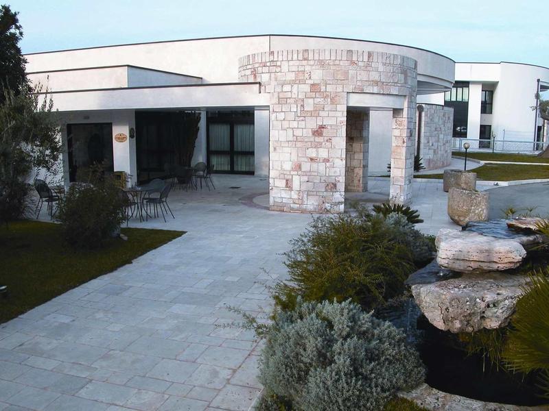 Modernes Haus mit runden und rechteckigen Formen, Steinplattenweg und gepflegtem Garten.