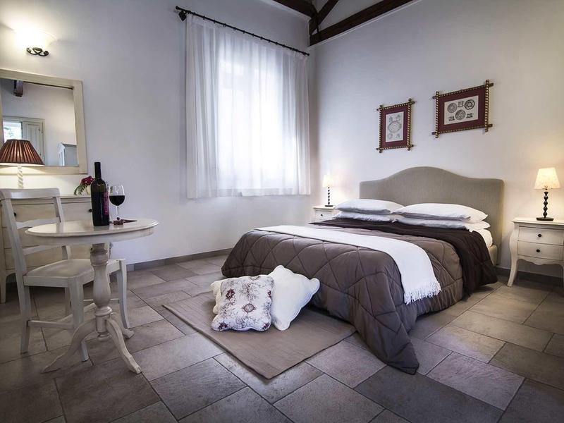 Helles Schlafzimmer mit großem Bett, weißen Möbeln, Kissen, Teppich und Tageslicht durch Fenster.