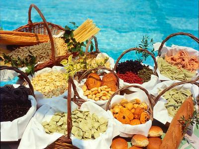 Verschiedene Körbe mit verschiedenen getrockneten Früchten, Nudeln und Gewürzen auf blauem Hintergrund.