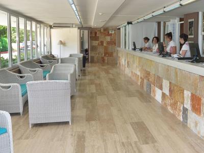 Hall d'hôtel lumineux avec espaces assis et réception le long d'un mur avec revêtement.