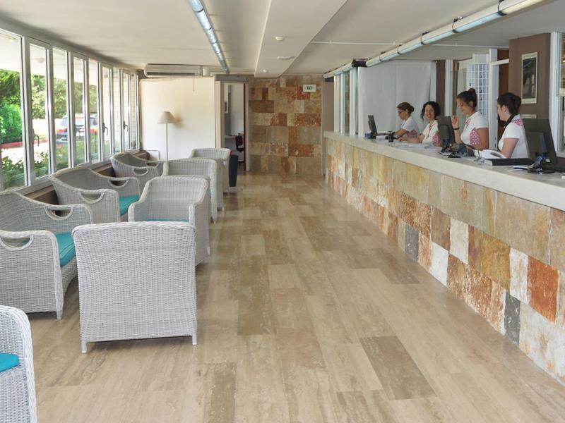 Hall d'hôtel lumineux avec espaces assis et réception le long d'un mur avec revêtement.