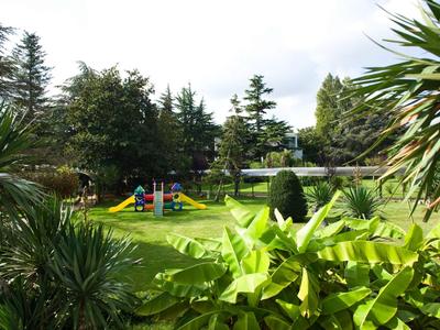 Grüner Garten mit Spielplatz und Bäumen in einer Ferienanlage