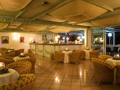 Gemütliche Hotelbar mit gepolsterten Sesseln und Tischen auf gefliestem Boden.