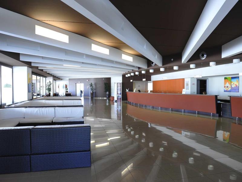 Modern hotel lobby with reception desk and seating areas under exposed beams.