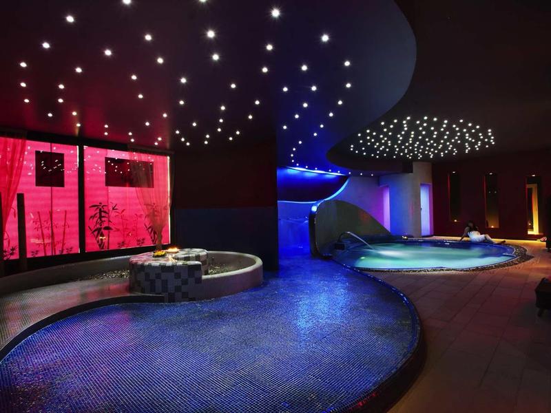 Modern indoor pool with atmospheric LED lighting and relaxing seating areas.