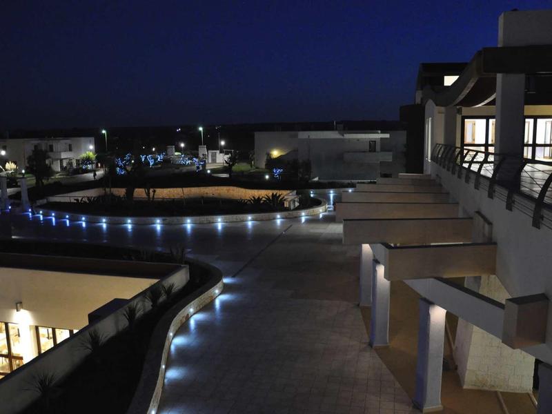 Modern hotel area at night with illuminated walkway and buildings.