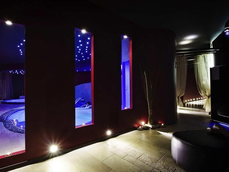 Dimly lit wellness area with illuminated hot tub and curtained relaxation space.
