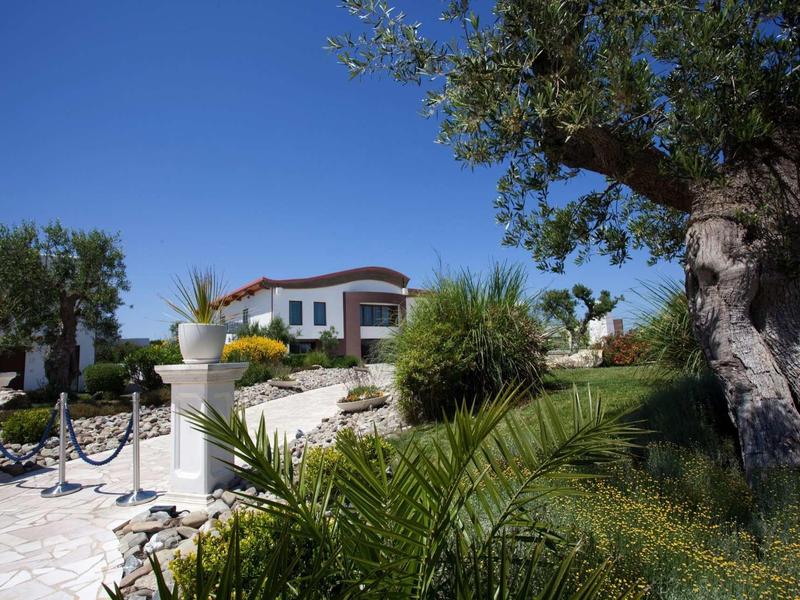 White house with red roof and well-kept garden under clear blue sky.