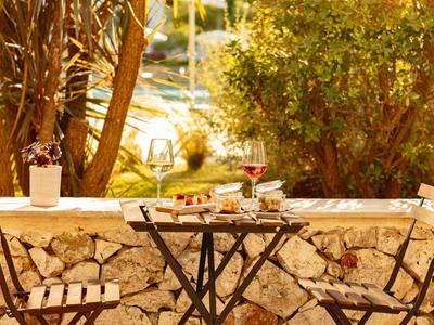 Kleiner Gartentisch mit zwei Klappstühlen vor einer Steinmauer, umgeben von Pflanzen.