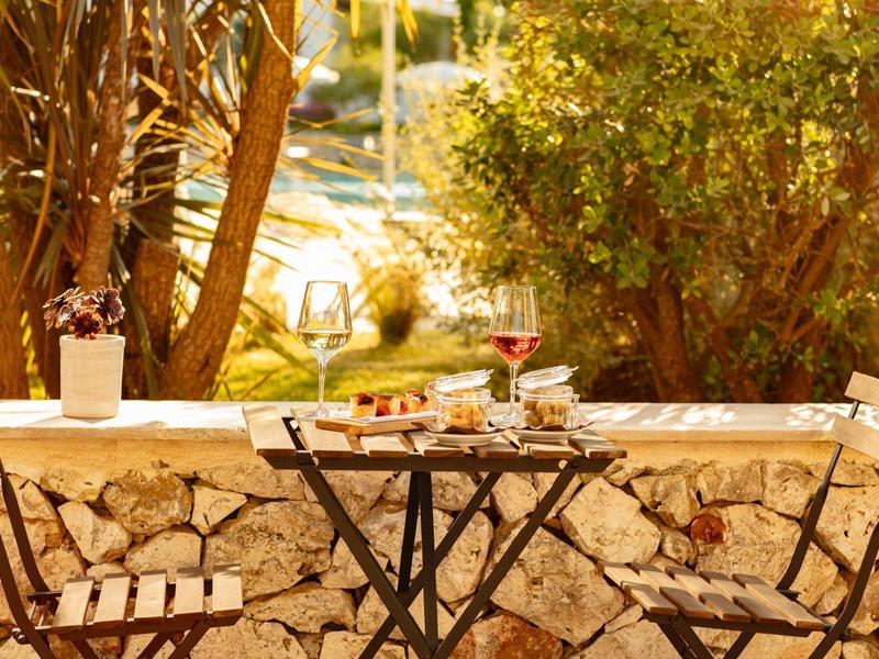 Kleiner Gartentisch mit zwei Klappstühlen vor einer Steinmauer, umgeben von Pflanzen.