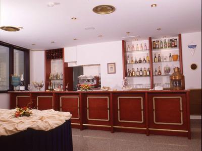 Moderne Hotelbar mit Holztresen, Regalwänden voller Flaschen und gedecktem Buffet im Vordergrund.