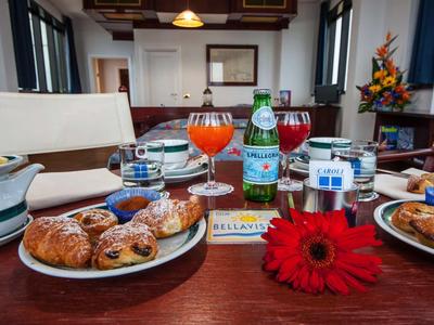 Ein gedeckter Tisch mit Gebäck, Getränken und einer roten Blume in einem gemütlichen Innenbereich.