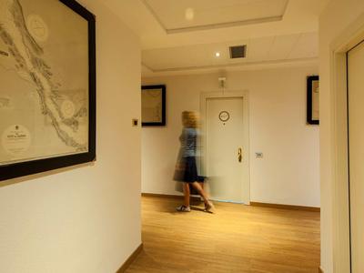 Flur mit hellen Wänden, Holzboden, mehreren Türen und einem unscharfen Mann in Bewegung.